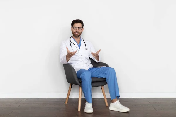 Przystojny Lekarz Średnim Wieku Mundurze Siedzi Krześle Rozmawia Przed Kamerą — Zdjęcie stockowe