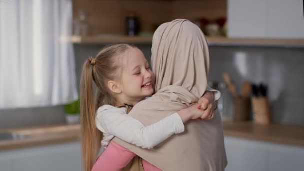聪明的孩子的爱 可爱的小女孩在厨房拥抱她可爱的妈妈 穆斯林女人在家里享受着与女儿的联系 动作缓慢 — 图库视频影像