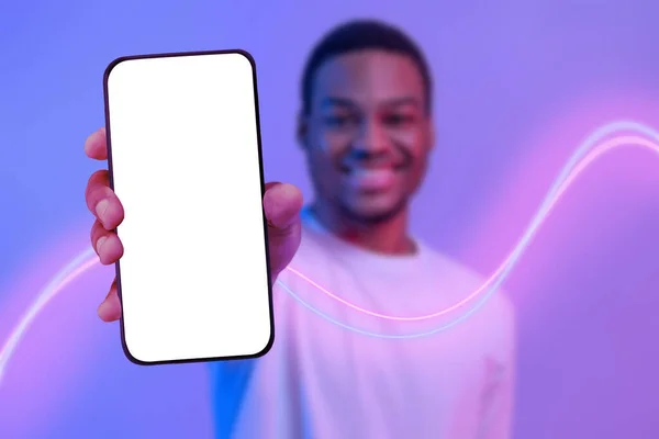 笑顔ハンサムな若いアフリカ系アメリカ人の男ショー真新しいスマートフォンで白の空白の画面 お勧めします素晴らしいオンラインオファー ネオンの光の中でポーズ コラージュ 広告のためのモックアップ — ストック写真