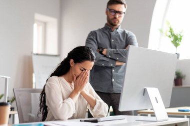 Yeni nesil Avrupalı patron, iş yerinde ağlayan kadın yöneticiye bilgisayarla bakar, modern ofis içinde hata bulur. Stres, baskı, iş hayatında sorunlar, finans, şirkette çalışma