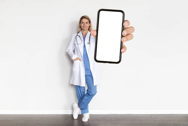 Medische Advertentie Glimlachende Doctor Lady Uniform Holding Big Blank Smartphone — Stockfoto