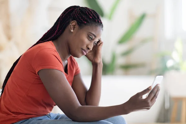 Besorgte Schwarze Frau Blickt Auf Smartphone Bildschirm Während Sie Hause — Stockfoto