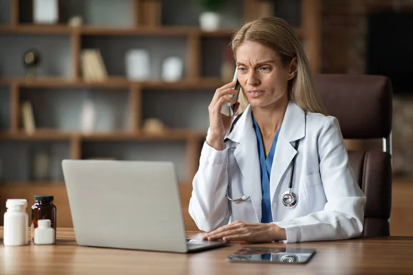 Aggódó Orvos Használja Laptopot Beszél Mobiltelefon Munkahelyen Klinikán Női Fizikus — Stock Fotó