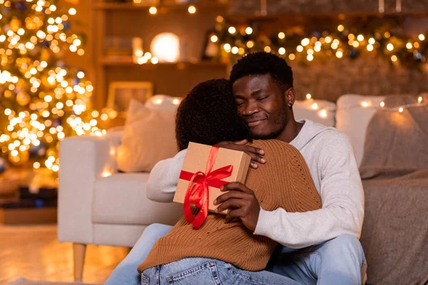 Χαίρομαι Που Νεαρός Αφροαμερικάνος Αγκαλιάζει Γυναίκα Του Και Κρατάει Κουτί — Φωτογραφία Αρχείου