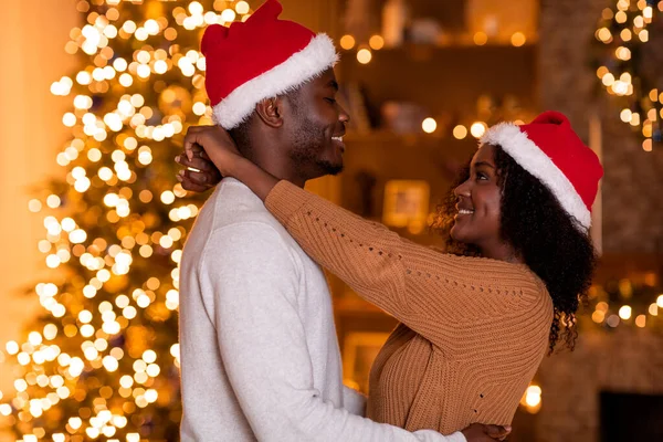 Sorrindo Cara Preto Milenar Feminino Chapéus Papai Noel Abraçando Quarto — Fotografia de Stock