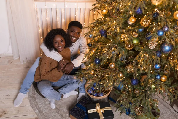 Sorrindo Millennial Abraços Casal Preto Senta Chão Decorar Árvore Natal — Fotografia de Stock