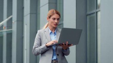 Her yerde temasta. Kendine güveni tam orta yaşlı iş kadını, laptopa el sallıyor ortaklarını selamlıyor, açık havada görüntülü sohbet ediyor, yavaş çekim, serbest alan