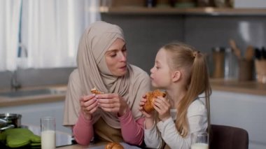 Ev yapımı hamur işi. Şirin küçük kız ve müslüman annesinin portresi taze çörek yiyor, el yapımı pişirme tadıyor, yakınlaştırıyor, yavaş çekimde.