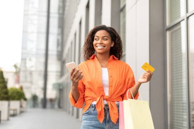Akıllı telefon, kredi kartı ve şehirde bir sürü paket dolusu alışverişi olan sıradan siyah bir bayanın boş bir yere bakmasına sevindim. Online alışveriş, reklam ve teklif, yaşam tarzı ve satış