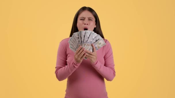 伟大的收入概念 年轻的孕妇躲在钱迷后面 把钞票扔向空中 享受着经济利益 橙色工作室背景 慢动作 自由自在的空间 — 图库视频影像