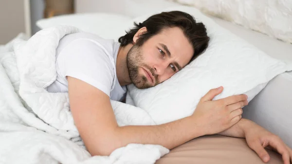 疲れ悲しい落ち込んだ千年紀の白人男性と頑固なことはできません眠りに白いベッドでは 寝室のインテリアの健康上の問題に苦しむ ストレス 不眠症 家での睡眠障害 — ストック写真