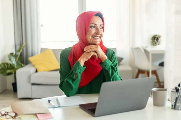 Pozitív Iszlám Hidzsábban Asztalnál Laptoppal Otthon Gondol Valamire Mosolyog Miközben — Stock Fotó