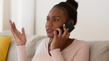 İlişki sorunları. Genç stresli Afro-Amerikan erkek arkadaşıyla akıllı telefondan tartışıyor, rahatsız ve üzgün hissediyor, çekimin izini sürüyor, yavaş çekim