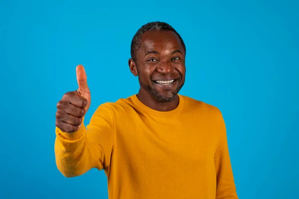 黄色の親指を示す肯定的な幸せな白髪の成熟したアフリカ系アメリカ人男性と笑顔青いスタジオの背景に隔離され 素敵なものをお勧めします コピースペース ジェスチャーコンセプト — ストック写真