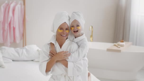 女性的乐趣 快乐的母亲和女儿 眼皮底下有胶原斑斑 头上有毛巾 笑着拍照 在家里享受美好的一天 慢动作 自由自在 — 图库视频影像