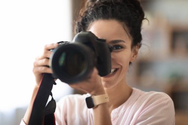 Kadın fotoğrafçı, kıvırcık saçlı, kıvırcık saçlı, DSLR ve akıllı hatunun evde ya da stüdyoda çalışıp profesyonel fotoğraflar çekerken çekilmiş yakın plan fotoğrafı. İş ve Meslek kavramı