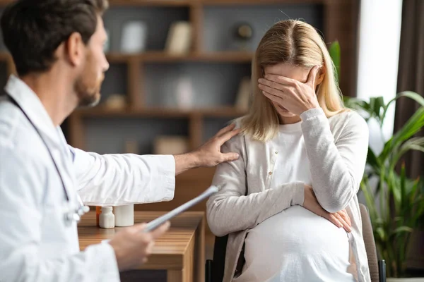 Gynecologist Doctor Comforting Upset Pregnant Woman During Meeting In Clinic, Male Reproductive Endocrinologist Soothing Crying Expectant Female Patient After Telling Her Bad Screening Result