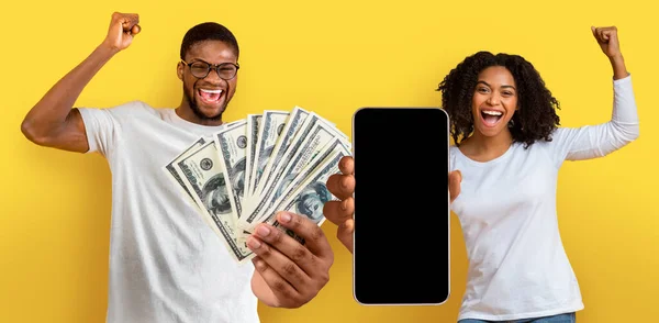 赠送的概念 这对年轻的黑人夫妇喜形于色 手里拿着大量的美元现金 用空白屏幕展示智能手机 摆出一副金光闪闪的样子 模仿着 — 图库照片