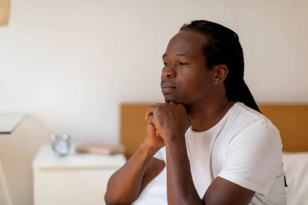 メランコリーの概念 寝室で休んでいる若い黒人男性の閉鎖肖像 ベッドの上に座っているアフリカ系アメリカ人の男 手にチンを休ませ 離れて見て うつ病を提供します — ストック写真