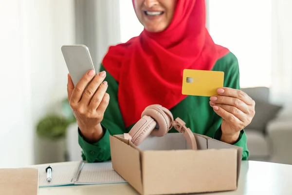 Modern Mature Muslim Woman Holding Credit Card Cellphone Unpacking Cardboard — Stock Photo, Image