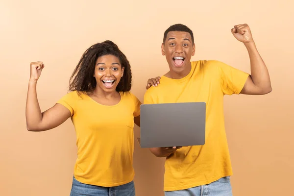 大きな勝利の概念 黒のカップルがノートパソコンを持ち 手を応援し 手を上げ 勝利を祝い 桃の背景で握りしめられた拳を振る — ストック写真
