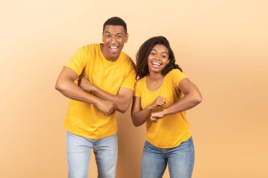 Neşeli Afro-Amerikan çifti Portarit dans ediyor ve oynaşıyor, birlikte eğleniyor ve şeftali stüdyosunun arka planında favori müziğin tadını çıkarıyor.