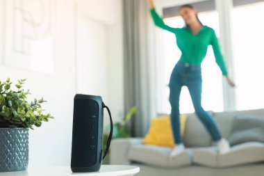 İnternette müzik hoparlörü ile müzik dinleyen, kanepede dans eden, harika müzik listesinin keyfini çıkaran, evinde dinlenen, seçici odaklanan tanınmamış bir kadın. Müzik aletleri konsepti