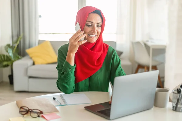 在家里的笔记本电脑上工作 看着电脑屏幕 与商业伙伴在智能手机上聊天 复制空间 这些都是积极成熟的穆斯林女性 — 图库照片