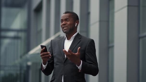 Profesjonell Middelaldrende Afroamerikansk Forretningsmann Trådløse Øretelefoner Som Snakker Telefonen Med – stockvideo
