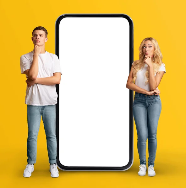 Pensiv Ung Par Stående Nära Enorma Smartphone Med Vit Skärm — Stockfoto