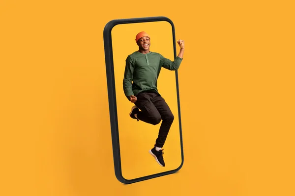 Glada Glada Millennial Svart Kille Hoppar Från Stora Smartphone Skärm — Stockfoto