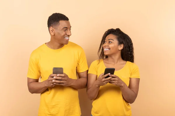 아프리카 미국인 배우자들은 핸드폰으로 인터넷을 하거나 친구들 채팅을 서로를바라보며 웃으며 — 스톡 사진