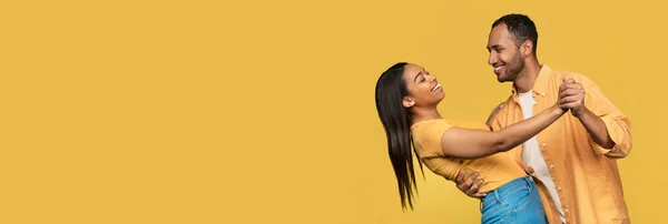 stock image Place For Ad. Happy Young Black Couple Dancing Together Over Yellow Background, Cheerful African American Man And Woman Having Fun And Looking To Each Other, Wide Horizontal Banner With Copy Space