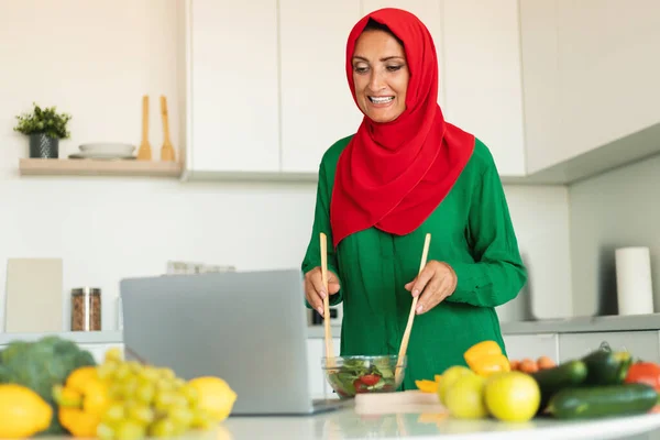 Mature Islamic Woman Making Salad Looking Laptop Computer Standing Modern — Stock Photo, Image