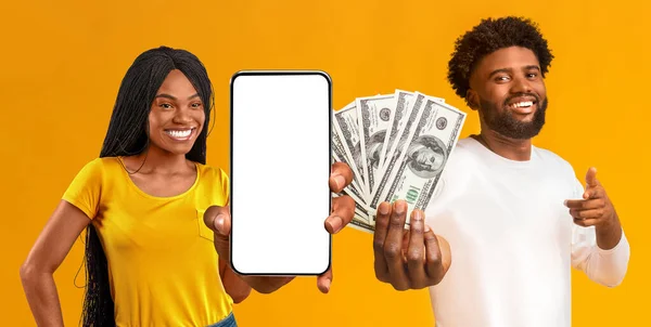 积极的非洲裔美国夫妇推荐漂亮的赌博移动应用 展示带有白色空白屏幕的手机 并在黄色工作室背景 全景等方面提供现金支持 — 图库照片