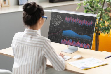Bilgisayar ekranında istatistikleri analiz eden genç iş kadını, ofiste oturan, finansal grafikler ve grafiklerle online çalışan kadın girişimci, veri analizi için iş yazılımını kullanıyor