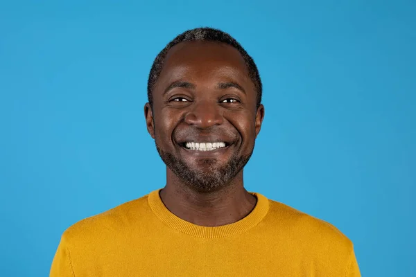 青いスタジオの背景の上に陽気に笑顔カジュアルな幸せな中年ハンサムな黒人男性のクローズアップ肖像画 白い歯 コピースペースを示しています 男性の肖像写真 人間の写真のコンセプト — ストック写真