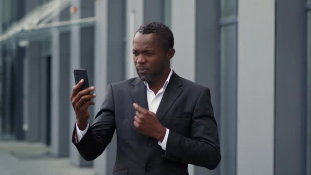 在线商务谈判 专业的中年黑人商人视频通过智能手机与合作伙伴聊天 讨论户外 慢动作 自由空间的项目细节 — 图库视频影像