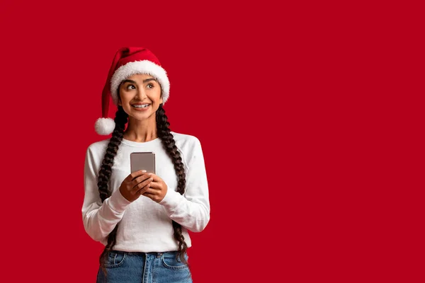Mujer Árabe Sonriente Santa Sombrero Sosteniendo Smartphone Mirando Hacia Otro —  Fotos de Stock