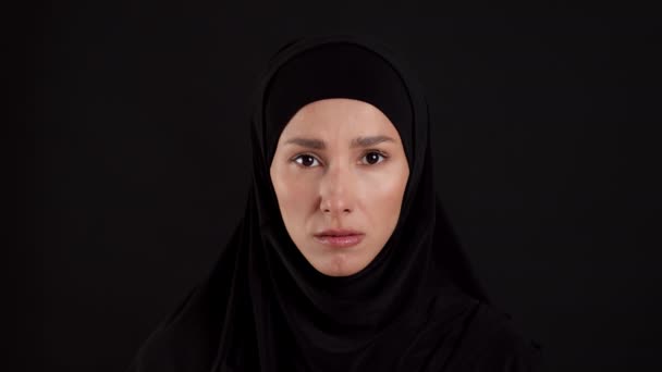 拯救伊斯兰妇女 对着传统头巾严肃地看着相机 在黑漆漆的工作室背景上摆姿势 慢动作的心烦意乱的穆斯林妇女的近照 — 图库视频影像