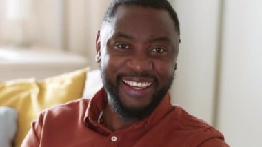 Video iletişim konsepti. Genç, mutlu, Afro-Amerikalı bir adamın video kaydı ya da interlocutorlarla konuşması, portreyi kapatın, yavaş çekim.