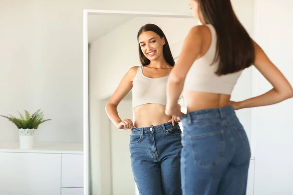 Веселая Молодая Женщина Позирует Джинсах Улыбается Своему Отражению Зеркале После — стоковое фото