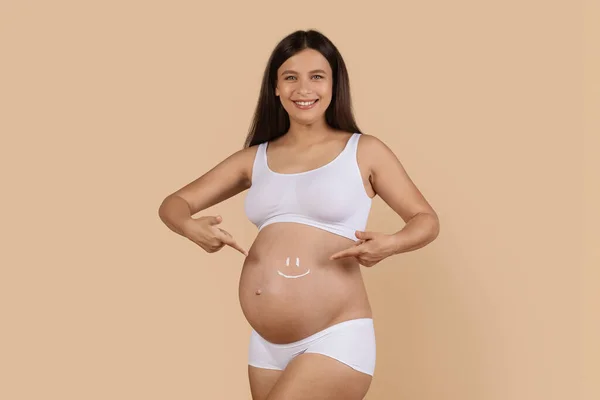 Pozitivní Těhotná Žena Spodním Prádle Ukazující Úsměv Obličej Vyrobený Smetany — Stock fotografie