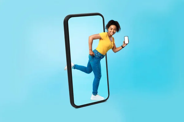 笑搞笑的千年非洲裔美国女性与智能手机与空白屏幕用尽大手机 孤立在蓝色背景 工作室 现代博客 应用程序和小玩艺儿 用于大规模销售 广告和提供 — 图库照片