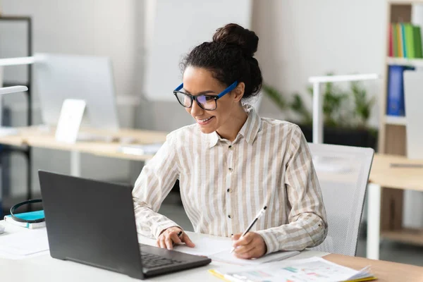 快乐年轻的拉丁女商人在办公室工作 坐在工作场所 使用现代电脑 做笔记 经理在网上为商业寻找新的创意 — 图库照片