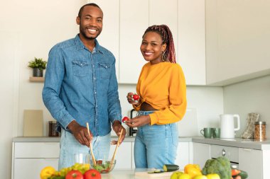 Afro-Amerikalı kadın ve erkek evde birlikte yemek pişiriyor, lezzetli sebze salatası yapıyor, kameraya gülümsüyor, mutfak içi, fotokopi odası. Sağlıklı yeme kavramı