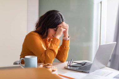 Uzaktan kumandalı Burnout. Masasında dizüstü bilgisayarla oturan depresyondaki genç Arap Kadın, Orta Doğulu Kadın Serbest Çalışan, Kafasına Yaslanan, Başarısızlık Projesi veya Çevrimiçi İş Sorunları