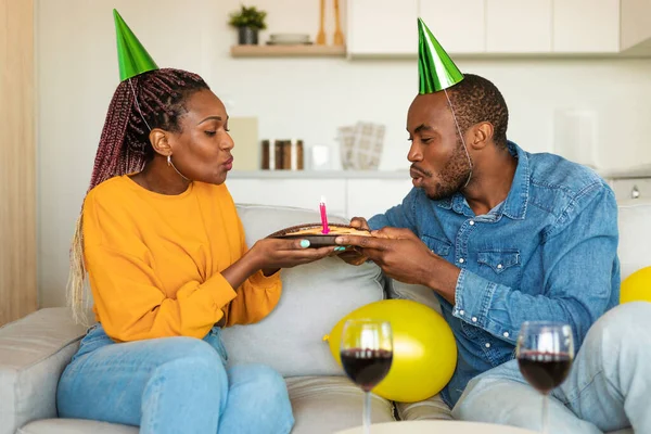 Excited Black Couple Party Hats Blowing Candles Birthday Cake Drinking — Stock Photo, Image