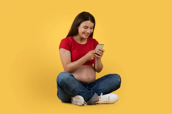 Ευτυχισμένη Νεαρή Έγκυος Γυναίκα Που Χρησιμοποιεί Smartphone Ενώ Κάθεται Στο — Φωτογραφία Αρχείου