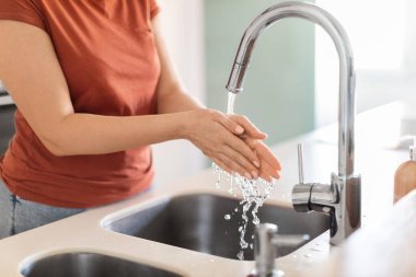 Genç bir kadının mutfak lavabosunda ellerini yıkarken, kadınlara dokunurken, akıntıyla oynarken, evde temizlik yaparken, ev işlerinin keyfini çıkarırken,